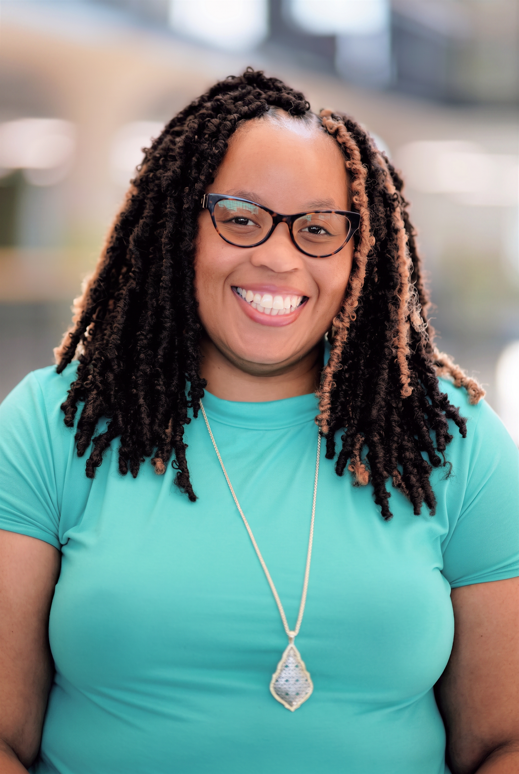 Headshot of Nikki Wallace wearing a teal shirt and a necklace, smiling warmly